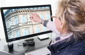 Uma mulher colocando o dedo na tela de um monitor.